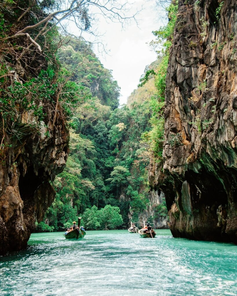 people riding on boat on river between rocky mountain during daytime